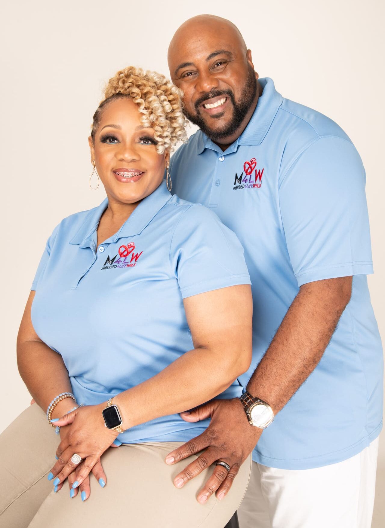 A smiling couple wearing matching light blue polo shirts.
