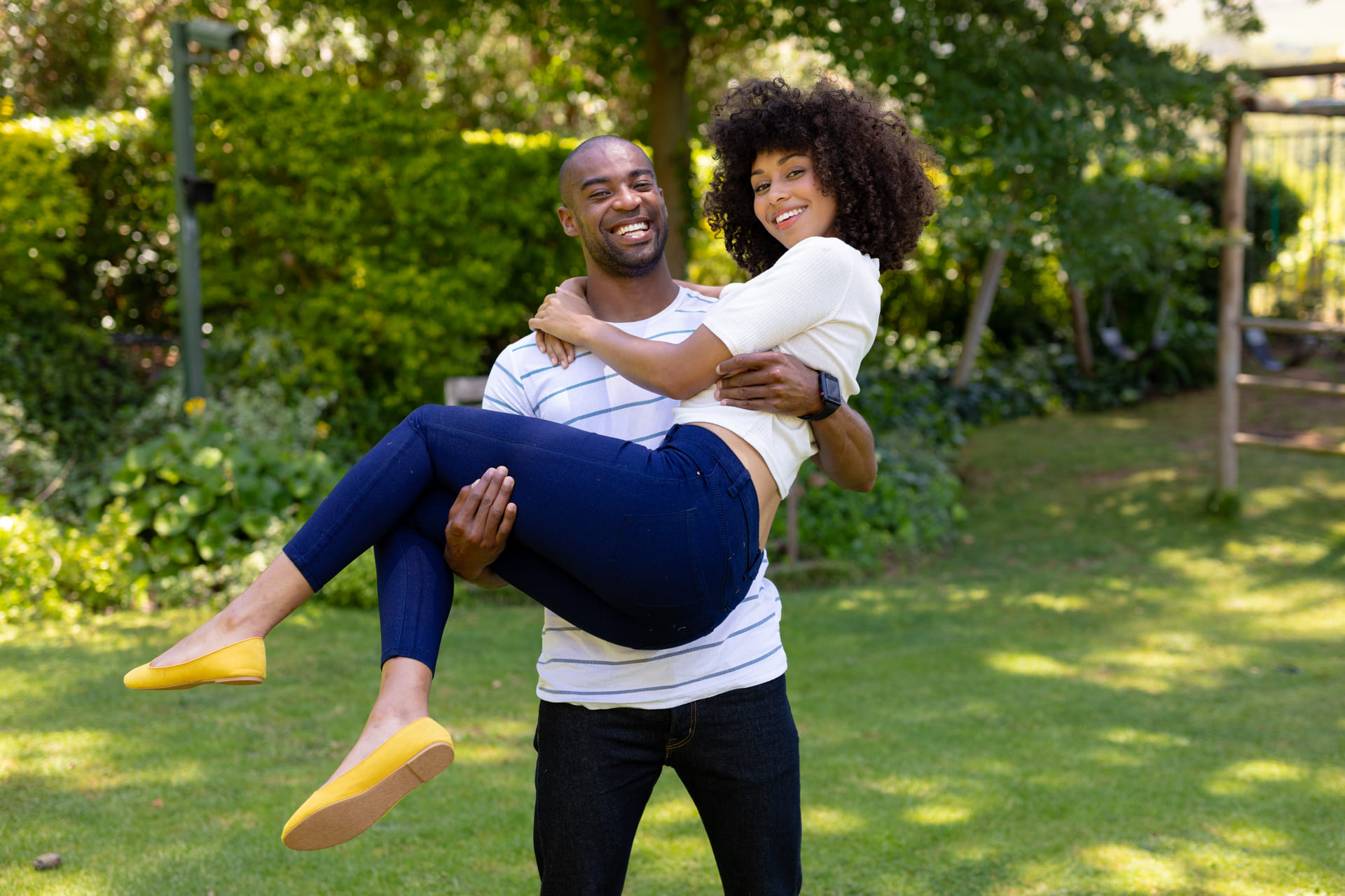 Man joyfully lifting a smiling woman in a park.